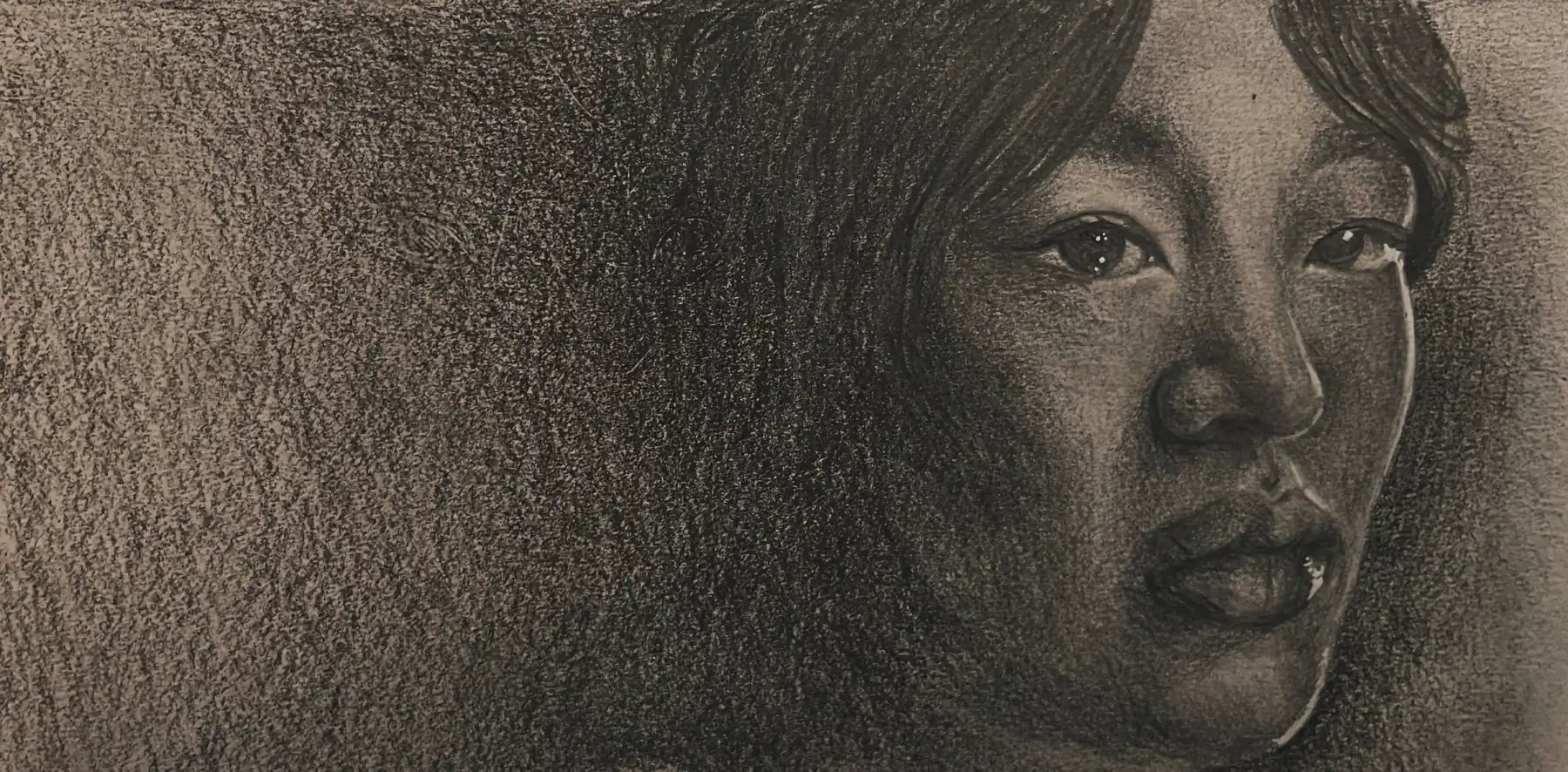 Charcoal portrait of a young woman, head and shoulders, emerging from a dense dark ground.