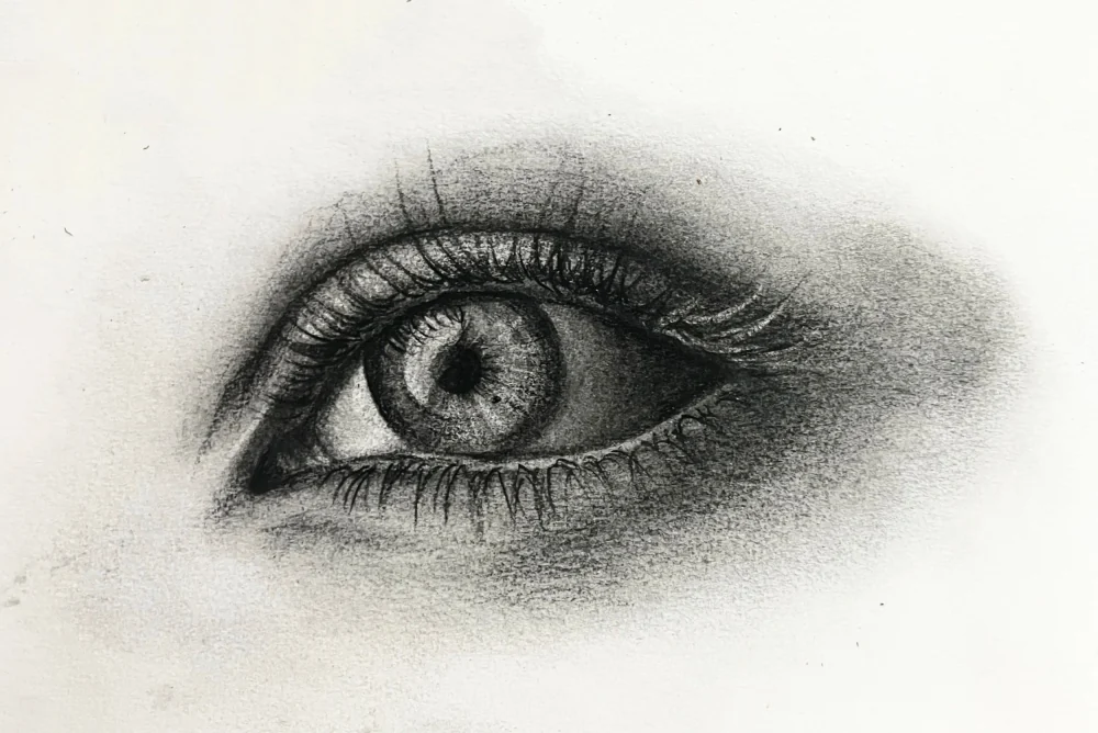 Graphite study of a single eye, rendered in soft tone with no outline.